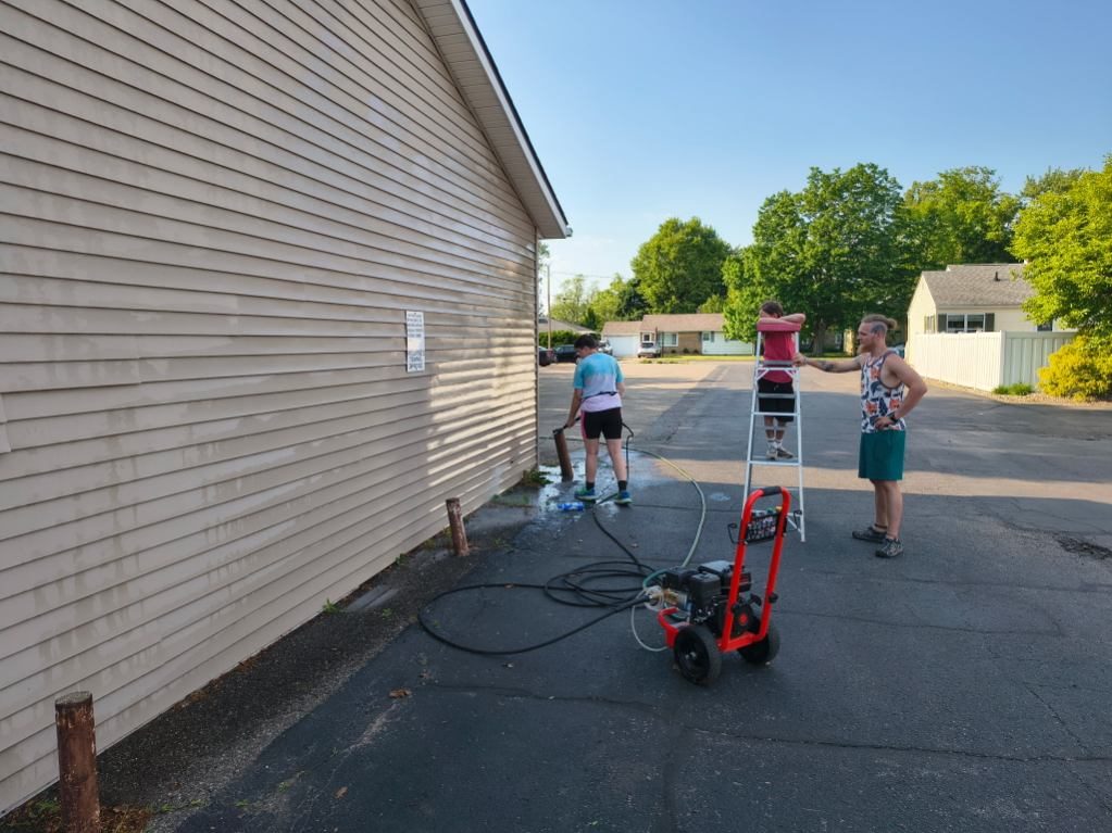 The Godvision Cleaning family working together pressure washing a building in Battle Creek, Michigan